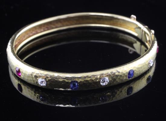 A planished 18ct gold, ruby sapphire and diamond hinged bangle, gross weight 20.4 grams.